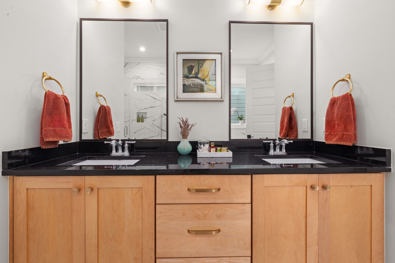 Elegant bathroom vanity featuring dual sinks, black countertop, and mirrors.
