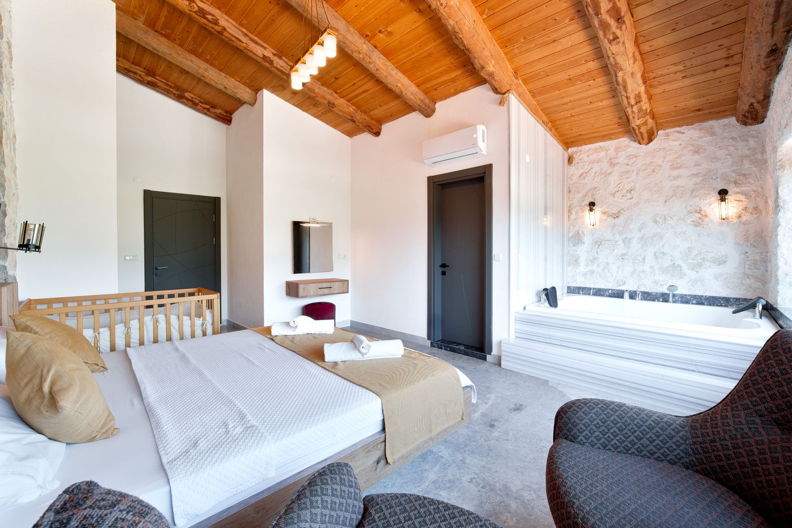 Spacious rustic-style bedroom with exposed wooden beams and a luxurious bathtub.