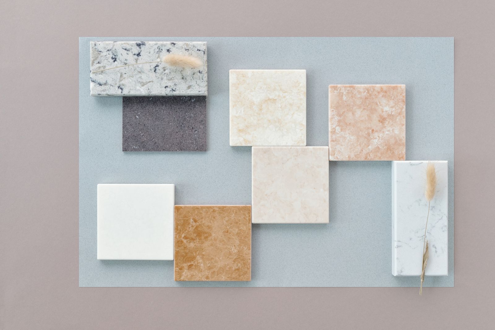 A flat lay of various marble tiles on a neutral background, showcasing diverse textures and colors.