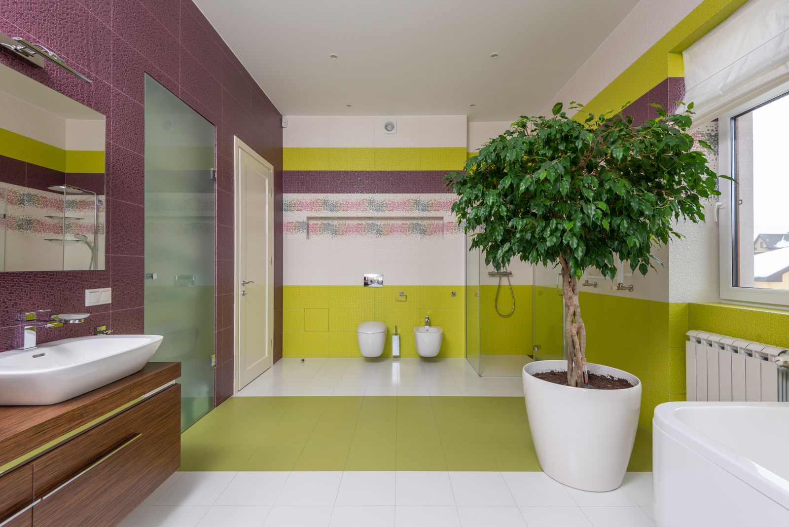 Interior of modern master bathroom with colourful walls and ceramic sink with mirror and potted plant near window